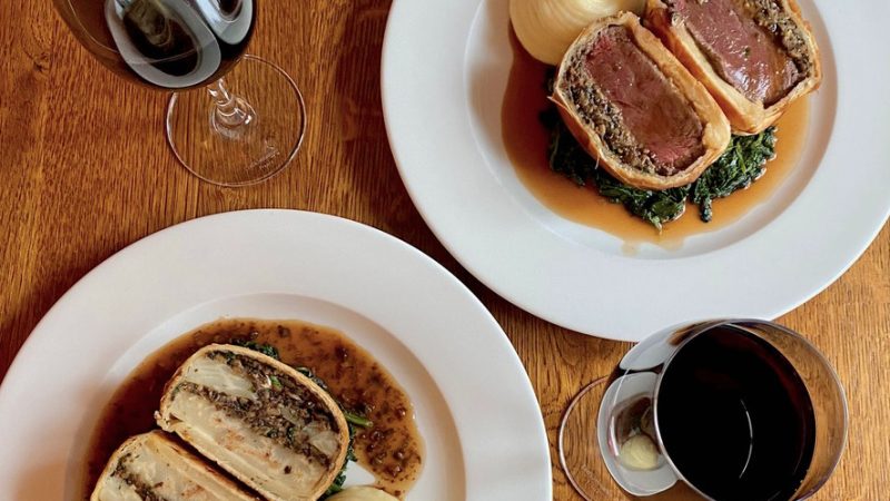 Wellington dish and red wine, served on a wooden table at Peach Pubs.